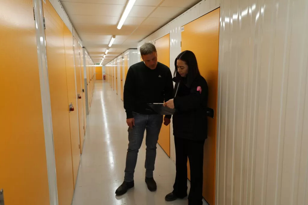 Staff member and customers looking at self storage units